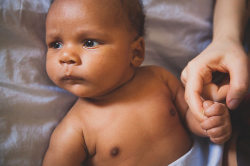 Lifestyle photo of a baby while he holds onto his mothers' finger