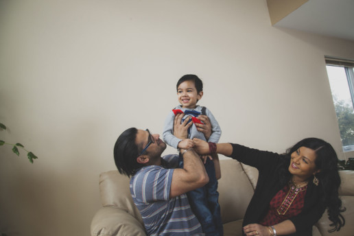 lifestyle photo of a family playing with their young son in their beige living room in Montreal