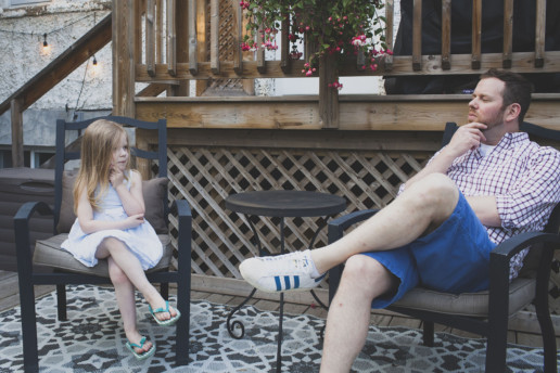 Father and daughter hold their chins and have a staring contest in their backyard in NDG
