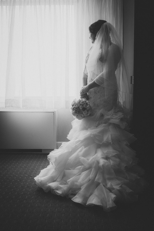 black and white portrait of the bride in her hotel room at Plaza Volare holding her bouquet