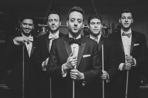 Groom and groomsmen take a serious photo with pool cues at the bar in Plaza Volare in Montreal