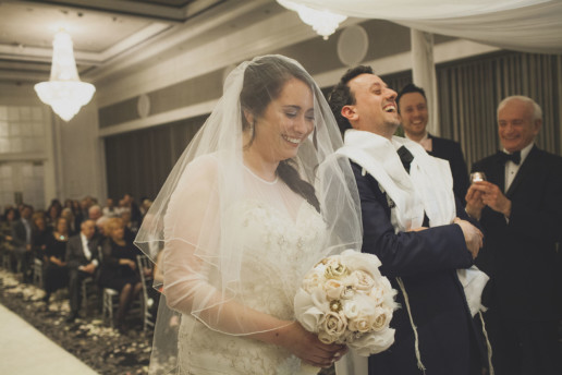 Couple laughs while under a chuppah at Jewish wedding at Plaza Volare