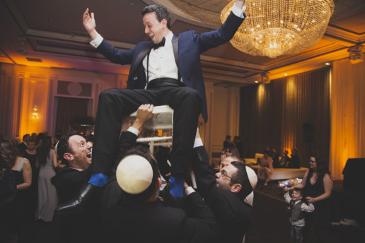 Groom on chair during hora at Plaza Volare