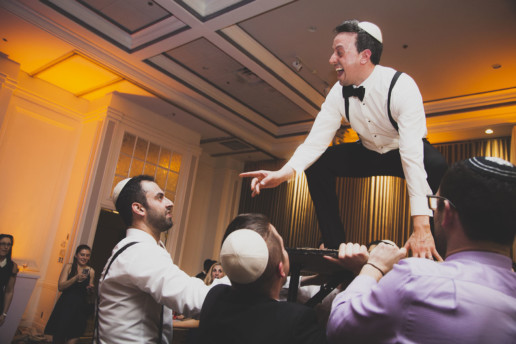Groom standing on a table during a hora dance in Montreal at Plaza Volare