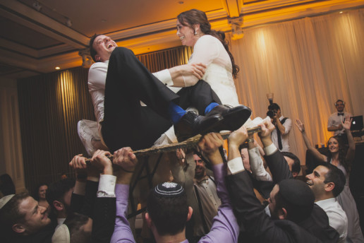 Bride and groom on a table during a hora at Plaza Volare for a Jewish wedding in Montreal