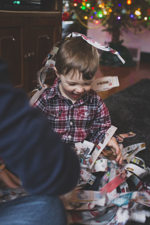A young boy playes with torn up newspaper in front of the family Christmas tree at home in Quebec
