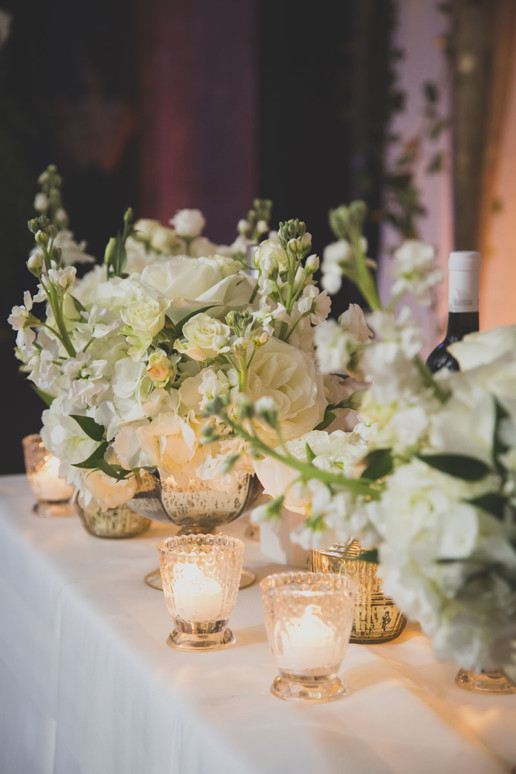 White and green flowers and candles with metallic vases set a neutral palette for the decor at Gare Viger for the montreal wedding