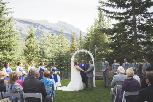 bride and groom hold hands during outdoor wedding cerermony at Rimrock Resort and Hotel with view of the mountains in Banff