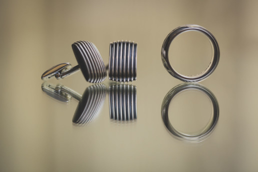 close up detail photo of the groom's cuff links and wedding ring on a mirrored surface