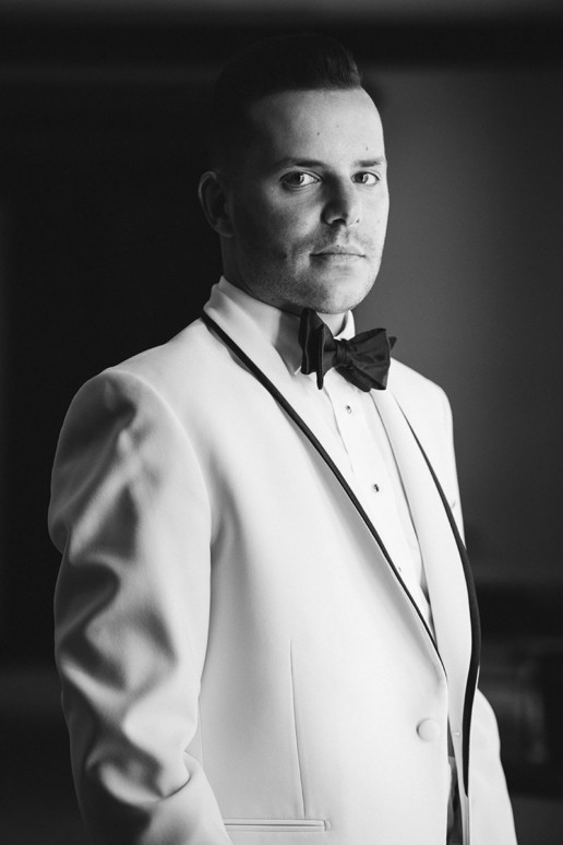 portrait of a groom in a tuxedo with a white smoking jacket