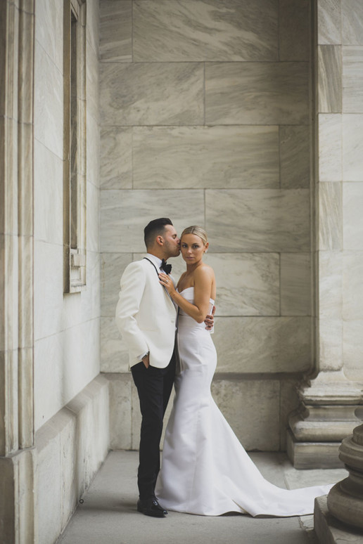 Groom kissing his bride on the forehead while holding her outside the museum of fine arts in Montreal