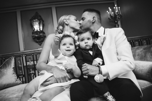 parents kissing while holding their twin babies dressed for their wedding in Montreal