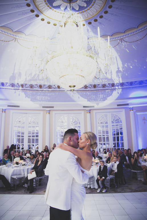 Couple share a kiss under the chandelier of the Oval Room during their first dance at the Ritz-Carlton Montreal