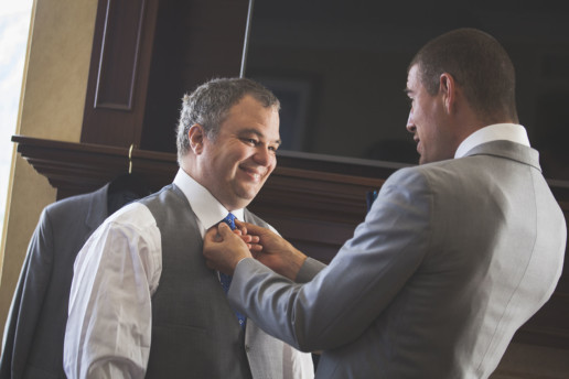 Groom has his tie adjusted by a groomsmen in the suite at the Rimrock Resort and hotel in Banff