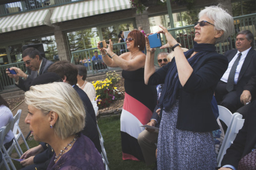 Guests take photos on their phones during wedding ceremony