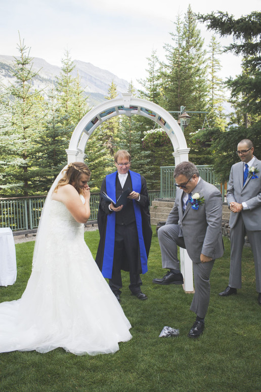 Groom is in mid-stride breaking the glass during a Jewish wedding ceremony in Banff