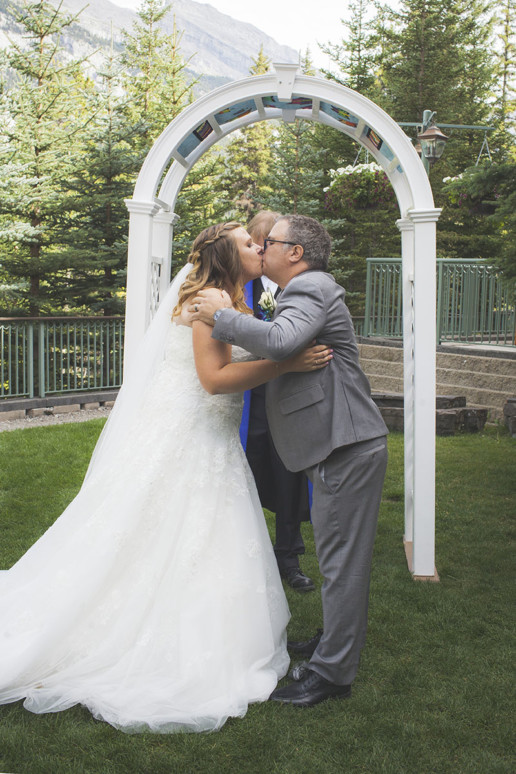 man and woman kiss during their outdoor wedding ceremony at Rimrock resort and hotel in Banff