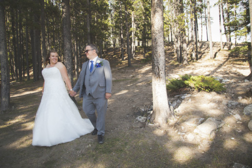man and a woman walk together on their wedding day in a forest in Alberta