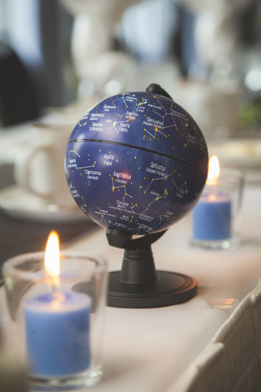 Detail of candles and table decor of a blue globes with constellations