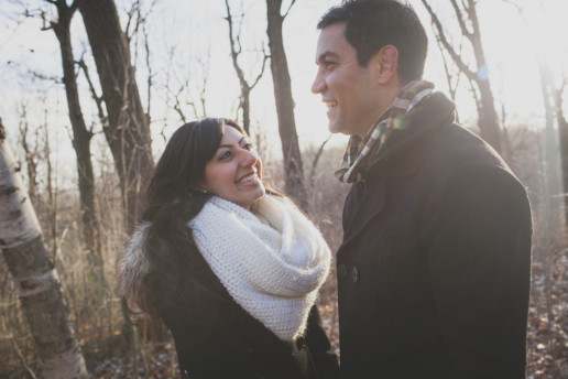 while on their engagement shoot a man and woman share a laugh in the woods of mont-royal in the sun