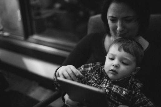 A mother and son sit together and watch something on an iPad at night in Quebec