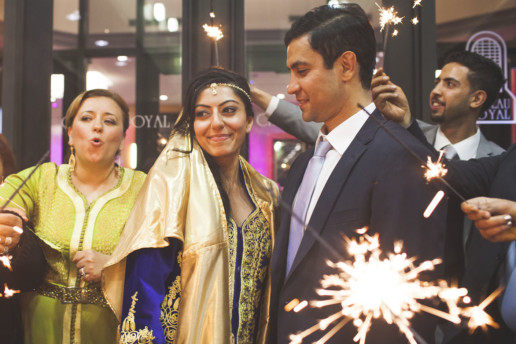 Bride and groom are surrounded by family and sparklers while wearing a blue and gold dress at montreal arabic wedding