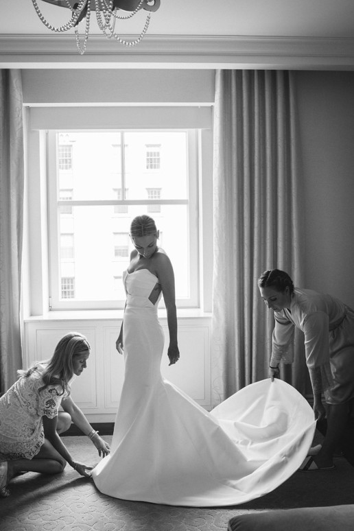 mother and maid of honor adjust brides wedding dress in suite at Ritz-Carlton Montreal