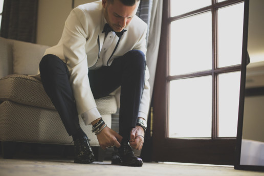 A man ties his glossy shoes before his wedding in his suite at the Ritz-Carlton hotel