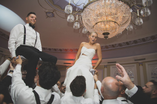 Bride and groom are lifted on chairs during the hora dance during a Jewish wedding at the Ritz-Carlton Montreal