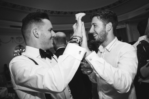 two men high five at wedding reception in the Oval Room