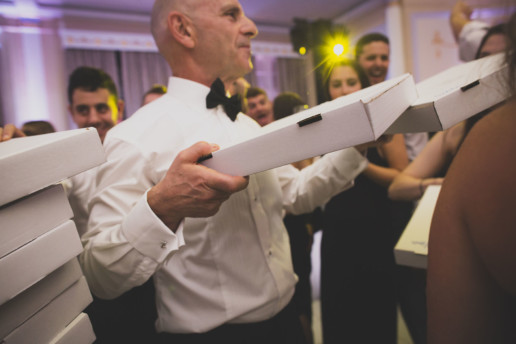 Father of the bride handing out pizza on the dance floor of the Oval Room during the party