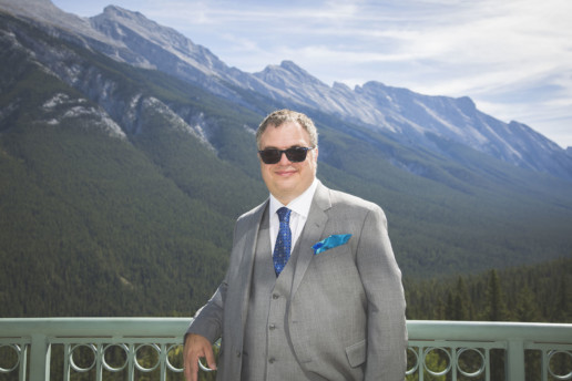 Portait of the groom from his balcony of his suite with Rocky Mountains in the background in Banff