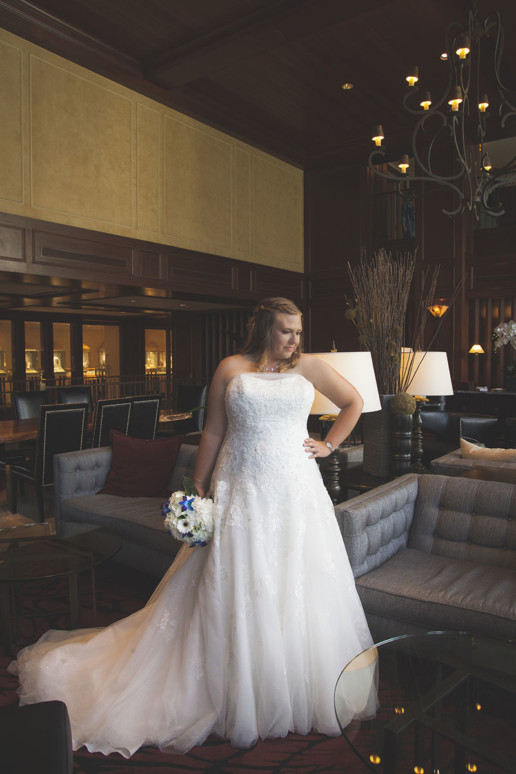 Bride poses in full length photo in wedding gown in the lobby of the Rimrock Resort and hotel in Banff