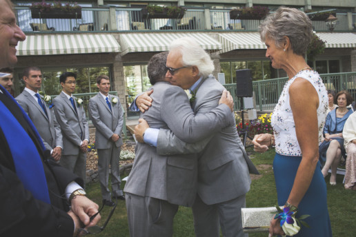 Father hugs the groom during the wedding ceremony at the Rimrock Resort and Hotel in Banff