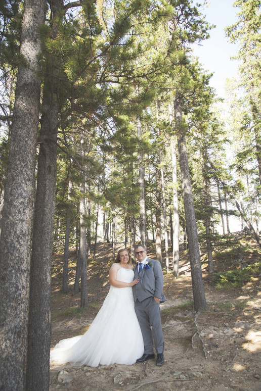 a couple stand together on their wedding day in a sunner forest in Alberta