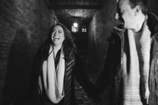 a woman laughs at night while walking with her fiance in an alley in old Montreal